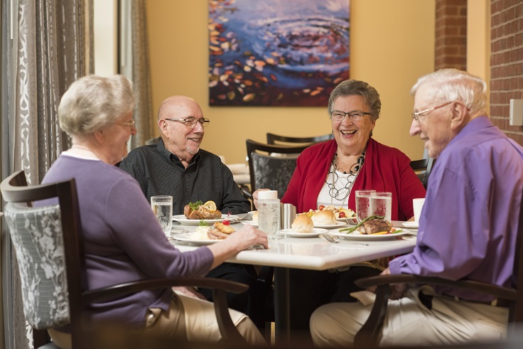 Two retired couples enjoying a meal together at Woodcrest Villa