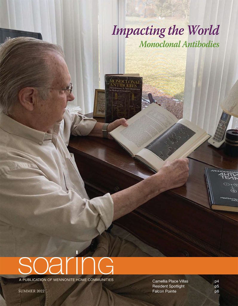 A resident reading a book on the cover of the Summer 2022 Soaring Newsletter